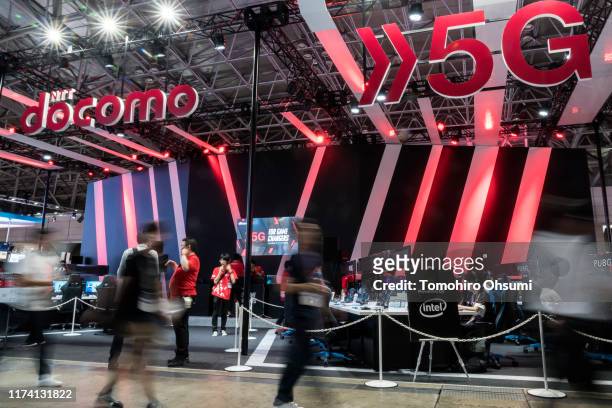 Attendees walk past the NTT Docomo Inc. Booth promoting the 5G networks on the business day of the Tokyo Game Show 2019 at Makuhari Messe on...