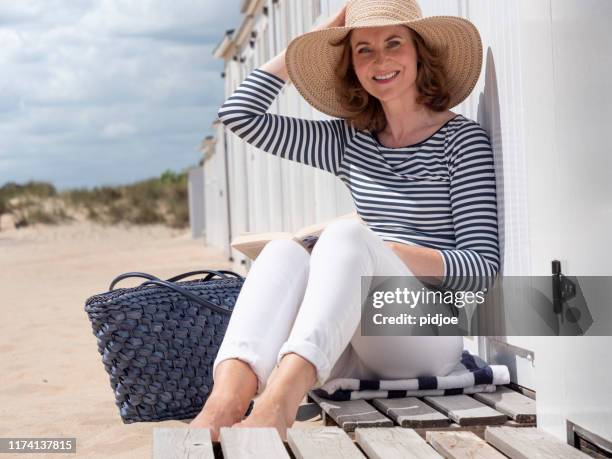 浜辺で本を読んでいる女性。 - barefoot redhead ストックフォトと画像