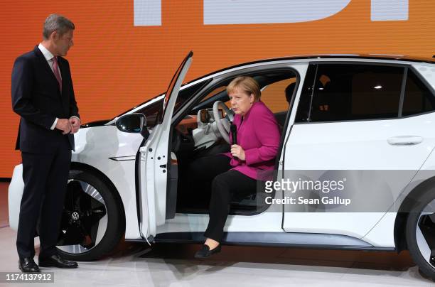 German Chancellor Angela Merkel gets out of a Volkswagen ID.3 electric car as Association of German Auto Industry head Bernhard Mattes looks on...