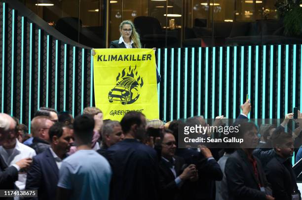 Greenpeace activist holds up a banner critical of the auto industry during a visit by German Chancellor Angela Merkel to the BMW stand on the opening...