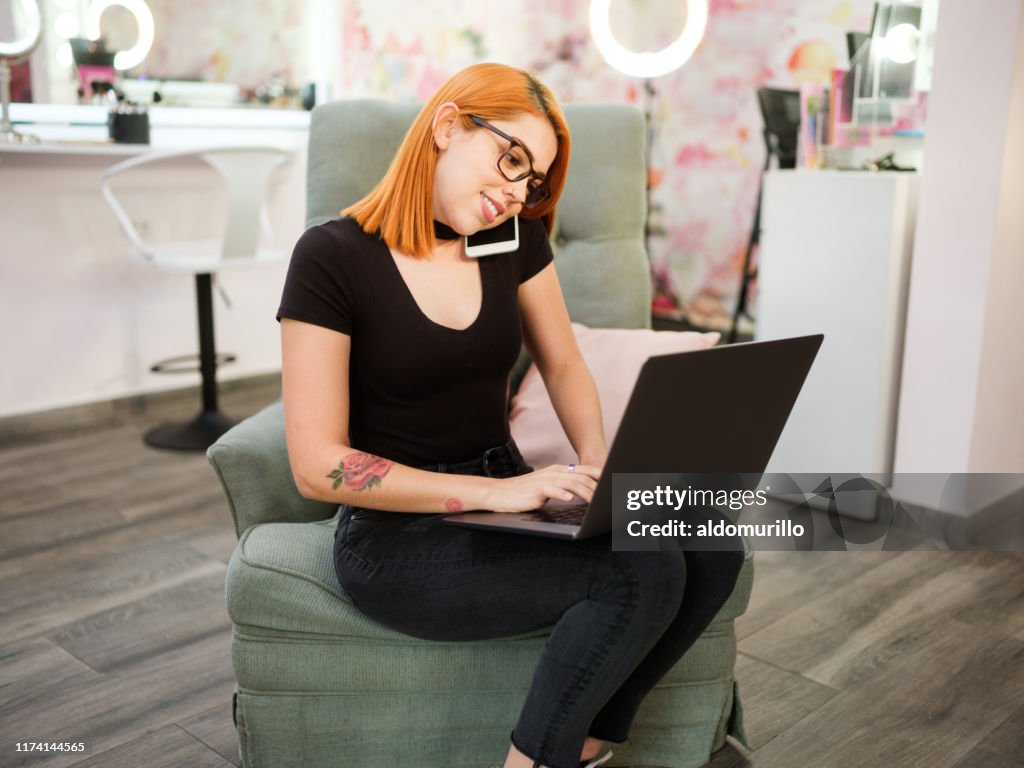 Busy young businesswoman using laptop and phone