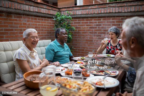 multi ethnic senior couple enjoying in vegan bbq dinner with friends - plastic free stock pictures, royalty-free photos & images