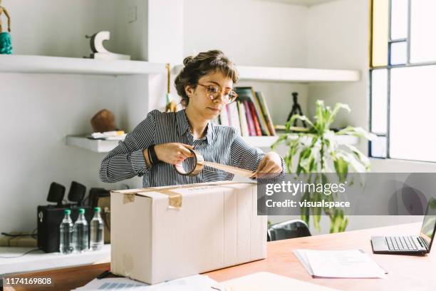 jonge vrouw het verzenden van een pakket - packing parcel stockfoto's en -beelden