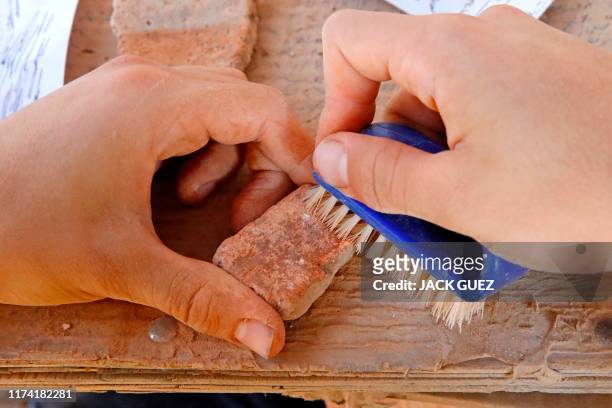 Worker brushes a pottery fragment unearthed at the archaeological site of En Esur where a 5000-year-old city was uncovered, near the Israeli town of...