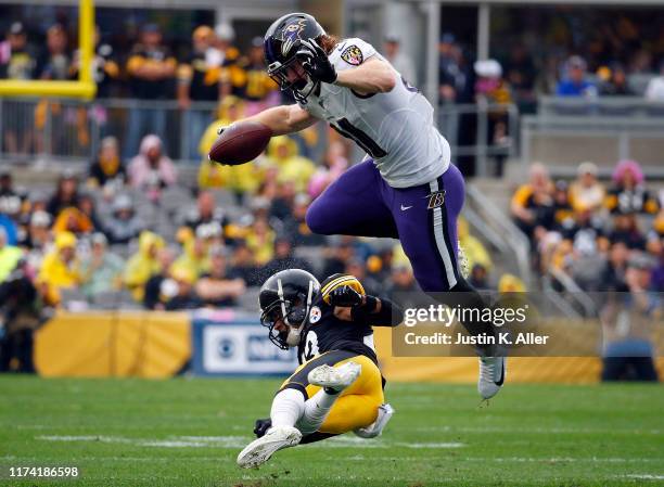 Hayden Hurst of the Baltimore Ravens hurdles Joe Haden of the Pittsburgh Steelers in the first half on October 6, 2019 at Heinz Field in Pittsburgh,...