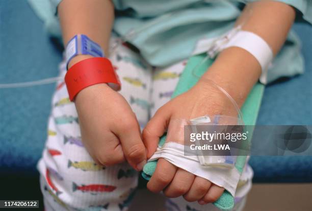 young boy in hospital bed showing intravenous lines in arm - sick child stockfoto's en -beelden