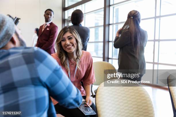 cheerful woman greets man during conference - diverse town hall meeting stock pictures, royalty-free photos & images