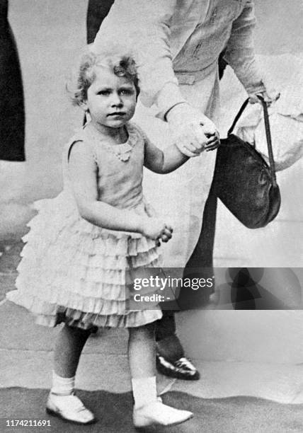 Picture of four-year-old Princess Elizabeth of Great Britain, wearing a summer dress, walking in an unknown location, in 1930.