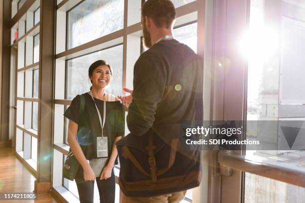 mujer de negocios sonriente hablando con un amigo durante el seminario - cordel acreditativo fotografías e imágenes de stock