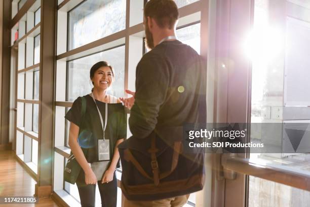 smiling businesswoman talking with friend during seminar - lanyard stock pictures, royalty-free photos & images