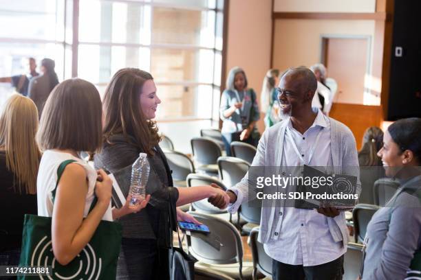 business colleagues greet during conference - town hall meeting stock pictures, royalty-free photos & images