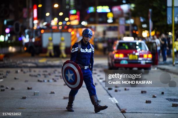 Man wearing a Captain America costume walks on a street as protesters and pedestrians gather near the Mong Kok police station in Hong Kong on October...