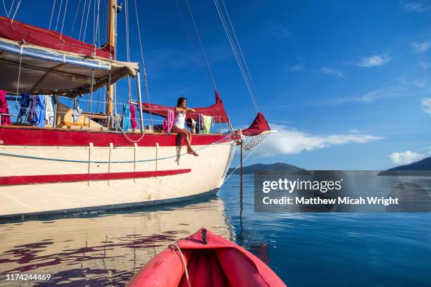 a woman poses on the bow of a sailboat. - isla de whitsunday fotografías e imágenes de stock