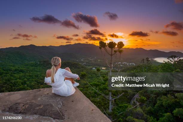a woman climbs atop a building to watch the sunset. - townsville fotografías e imágenes de stock