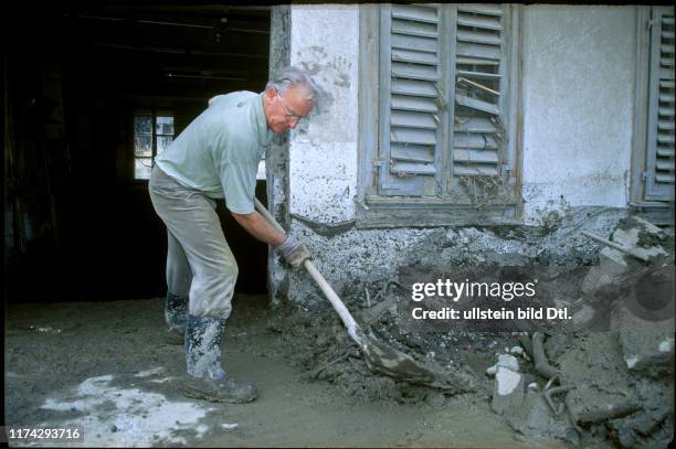 Dorfbewohner beim Aufräumen nach der Überschwemmung#Village inhabitant doing clearance works after the flood#