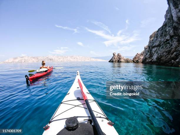 couple kayaking under the cliffs - sea kayak stock pictures, royalty-free photos & images