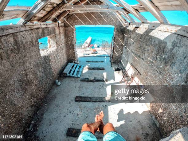 mann sitzt in einem alten strandhaus - schlechter zustand stock-fotos und bilder