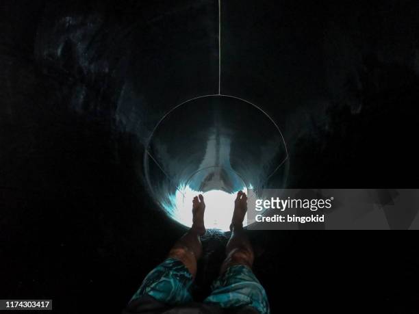 mann rutscht in wasserrutsche tunnel - wasserrutsche stock-fotos und bilder