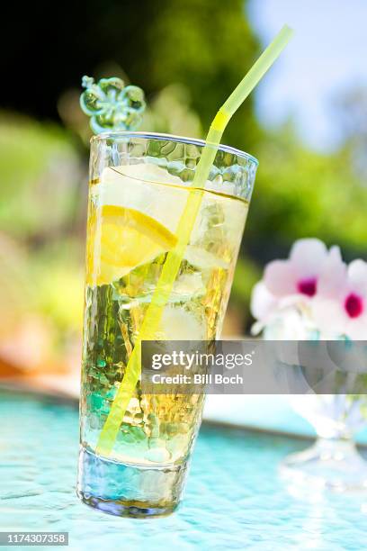 white wine spritzer with lemon slice, drinking straw, and swizzle stick poolside on a glass table - white wine spritzer stock pictures, royalty-free photos & images