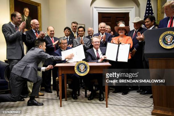 President Donald Trump watches as Japan's US Ambassador Shinsuke Sugiyama and US Trade Representative Robert Lighthizer participate in a signing of a...