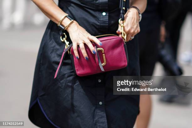 Guest wears a black dress, a bracelet, a raspberry-color bag, outside Acne Studios, during Paris Fashion Week - Menswear Spring/Summer 2020, on June...