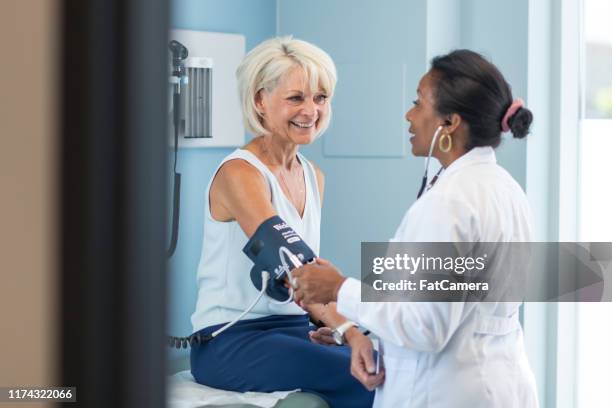 mature adult woman in medical consultation with female doctor - medicaid stock pictures, royalty-free photos & images