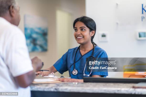 profesional médico saluda al paciente en la clínica - receptionist fotografías e imágenes de stock