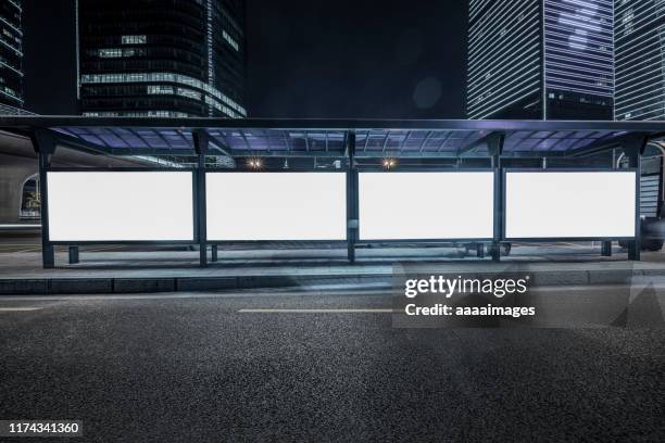 illuminated blank billboards at bus stop - billboard night photos et images de collection