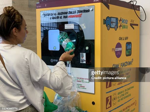 October 2019, Italy, Rom: A woman cashes old plastic bottles in a vending machine for subway and bus tickets. The passengers put the plastic bottles...