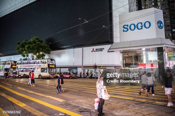 Pedestrians walk across a street in front of the Sogo department store in the Causeway Bay district of Hong Kong, China, on Monday, Oct. 7, 2019. A...