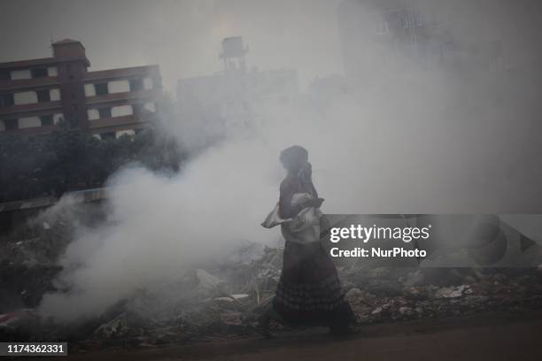 People seen moving as toxic garbage are burning beside a road near The Buriganga river in Dhaka, Bangladesh on 07 October 2019. Dhaka was named the...