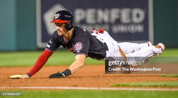 Washington Nationals shortstop Trea Turner dives into third base on a wild pitch in the sixth inning against the Los Angeles Dodgers during game four...