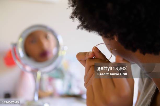 woman putting on hoop earring - earrings stockfoto's en -beelden