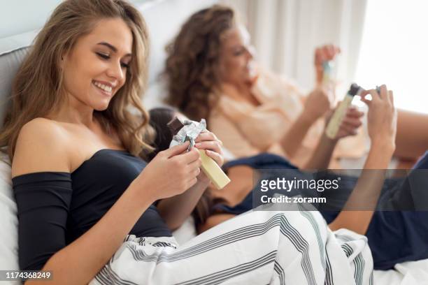 smiling young woman opening a bar of chocolate next to her friends - open chocolate bar stock pictures, royalty-free photos & images