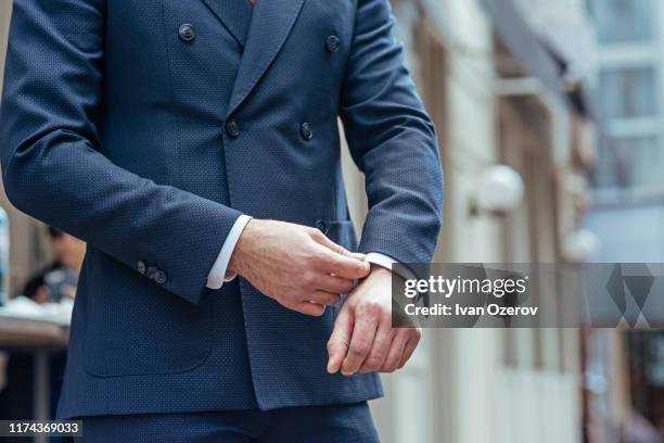 man wearing double-breasted suit adjusting his cuff - giacca blu foto e immagini stock