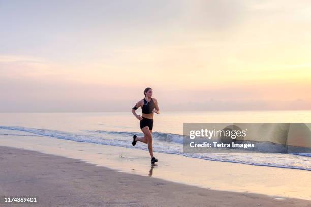 woman jogging on beach at sunset - funkwelle stock-fotos und bilder