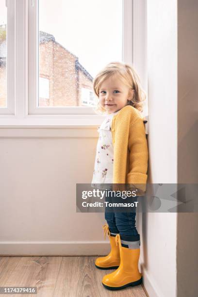 twee jaar oude baby thuis in een herfst regenachtige dag - standing in the rain girl stockfoto's en -beelden