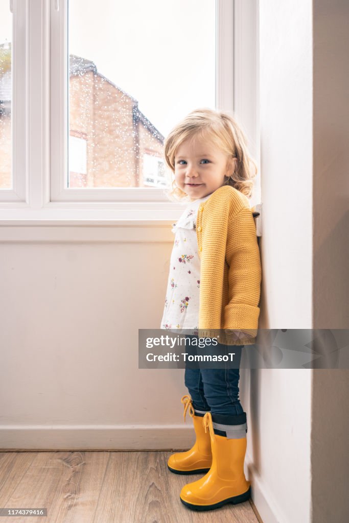 Two years old baby at home in a autumn rainy day