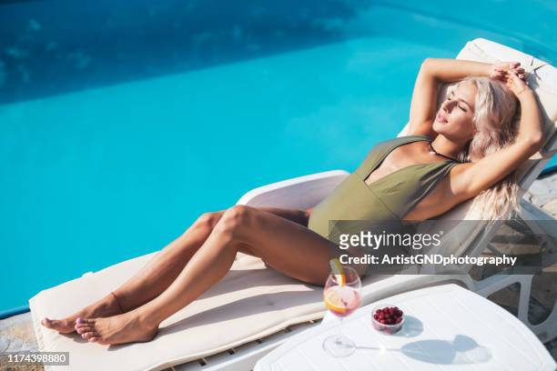 woman relaxing on lounge chair on poolside. - sun lounger stock pictures, royalty-free photos & images