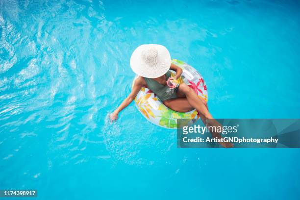 blick auf frau liegen auf aufblasbaren floß in schwimmbad - luftmatratze stock-fotos und bilder