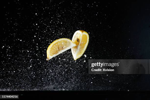 yellow lemon flying in mid air with water captured with high speed - lemon slices fotografías e imágenes de stock