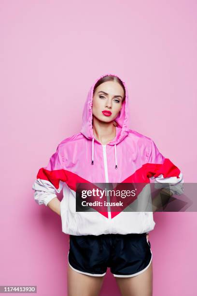 80's style portrait of beautiful woman in oversized tracksuit against pink background - ladies shorts stock pictures, royalty-free photos & images