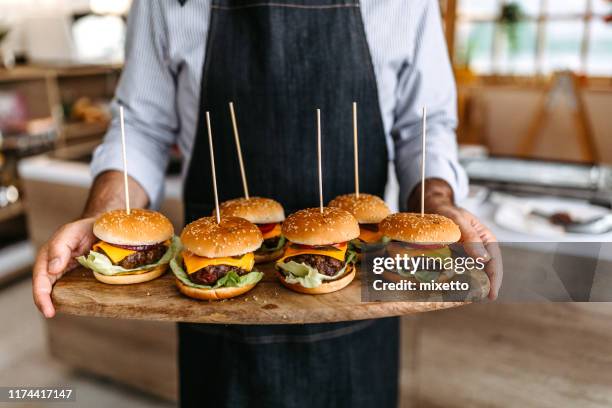 delicious slider-burgers on wooden tray in men hands - man tray food holding stock pictures, royalty-free photos & images