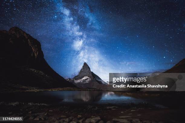 silhouette des menschen, der die milchstraße und millionen von sternen über matterhorn und see in den schweizer alpen genießt - matterhorn stock-fotos und bilder