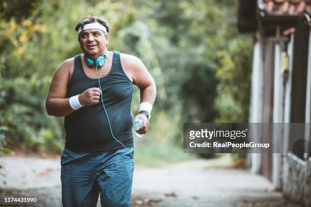 dikke man langzaam buiten lopen, actieve levensstijl als worstelen met obesitas - fat loss training stockfoto's en -beelden