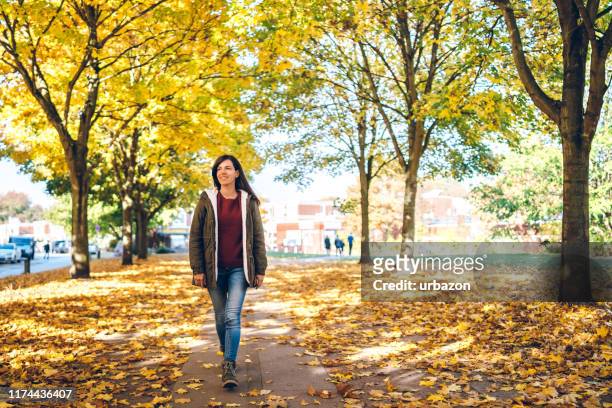 woman walking in a park - woman walks down street stock pictures, royalty-free photos & images
