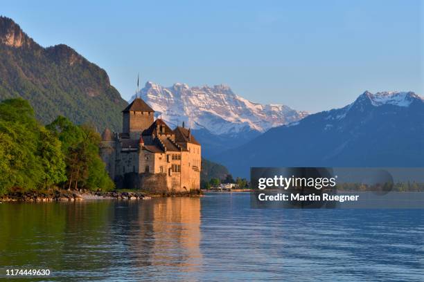 chillon castle (chateau de chillon) located on lake geneva at sunset with the mountain dents du midi in background, clear blue sky. chillon castle, montreux, lake geneva, canton of vaud, dents du midi, switzerland. - montreux stock pictures, royalty-free photos & images