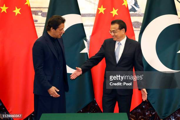 Pakistan's Prime Minister Imran Khan poses with Chinese Premier Li Keqiang during of a signing ceremony at the Great Hall of the People in Beijing on...