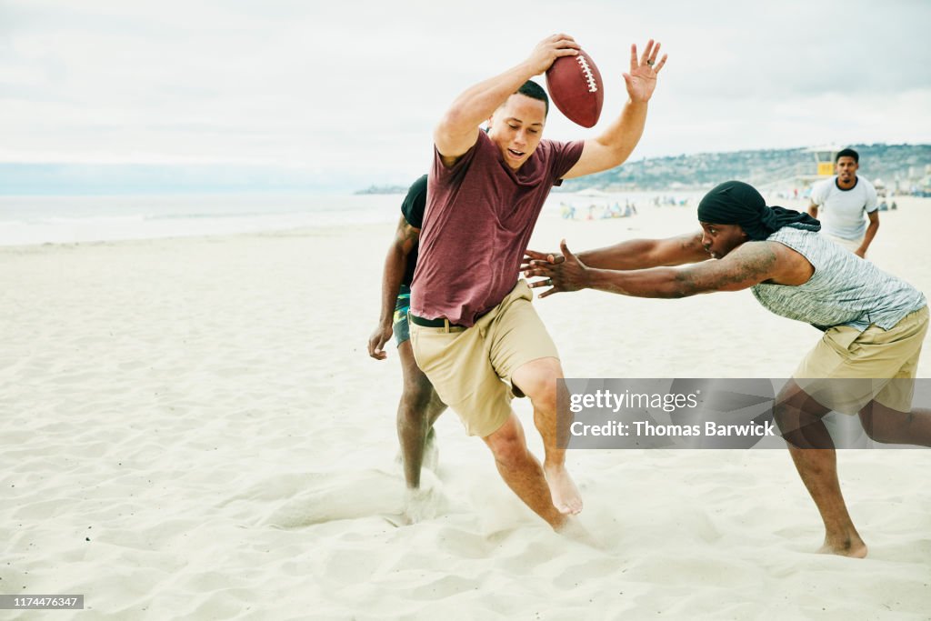 Man trying to avoid defenders during touch football game on beach