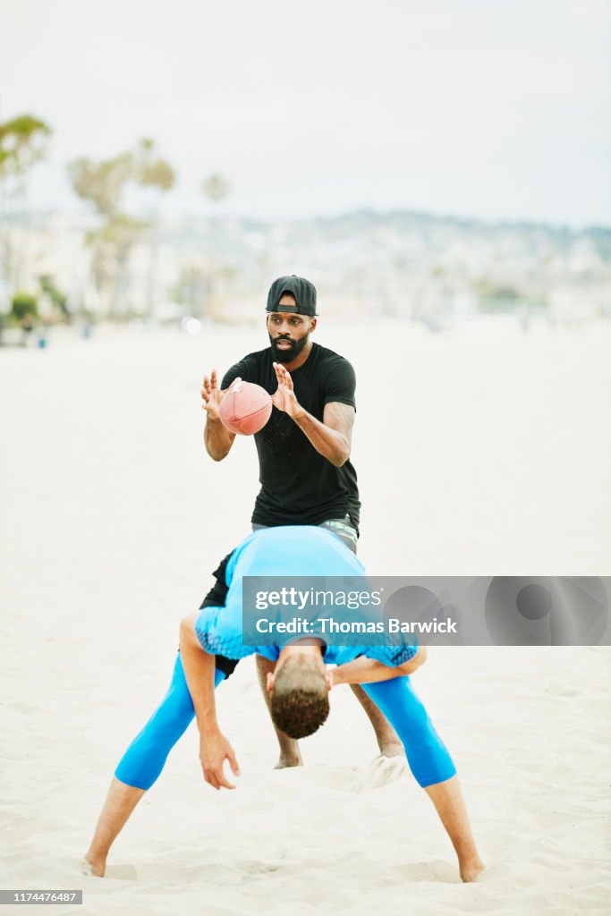 Quarterback taking snap during football game on beach with friends